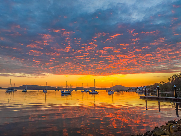 Aerial sunrise over the water with boats and clouds