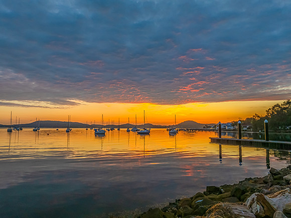 Aerial sunrise over the water with boats and clouds