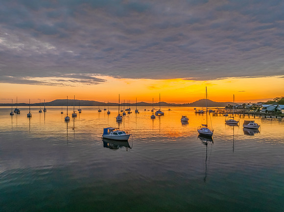 Aerial sunrise over the water with boats and clouds