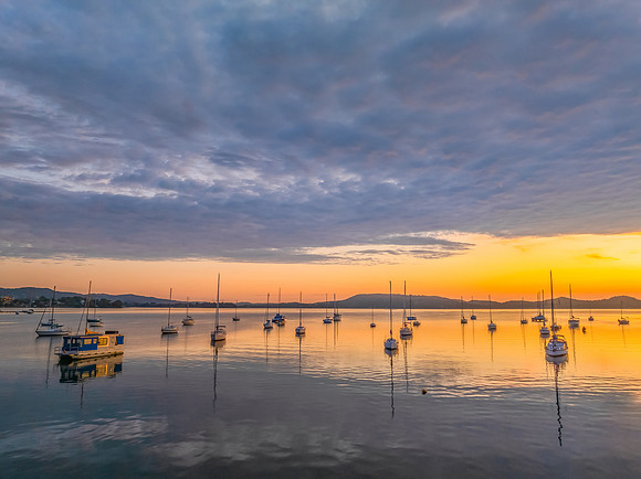 Aerial sunrise over the water with boats and clouds