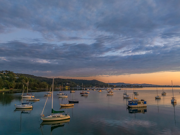Aerial sunrise over the water with boats and clouds
