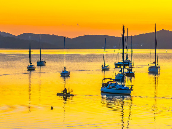 Aerial sunrise over the water with boats and clouds