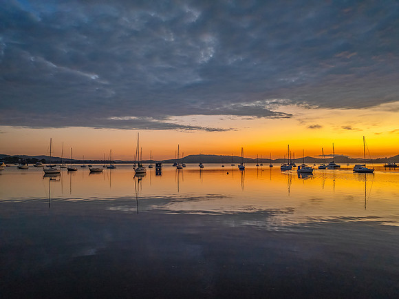 Aerial sunrise over the water with boats and clouds
