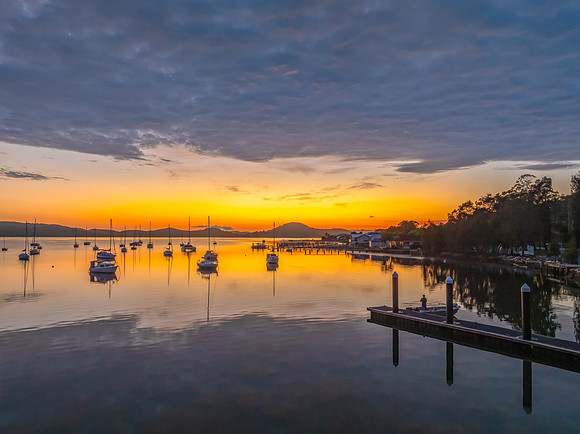 Aerial sunrise over the water with boats and clouds