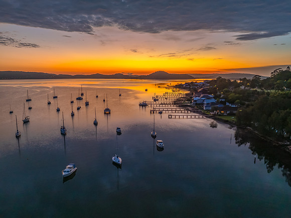 Aerial sunrise over the water with boats and clouds