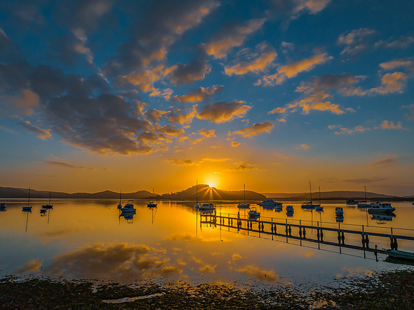 Aerial sunrise waterscape with boats, reflections and low cloud