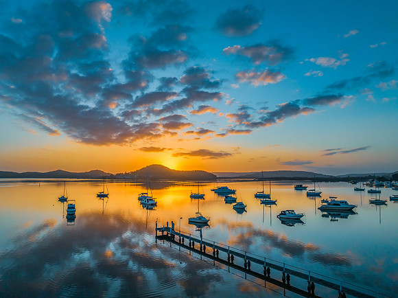 Aerial sunrise waterscape with boats, reflections and low cloud