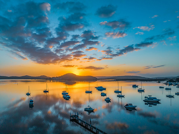 Aerial sunrise waterscape with boats, reflections and low cloud