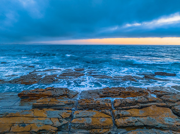 Cloudy sunrise over the ocean with rock platform