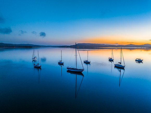 Aerial sunrise waterscape with boats, reflections and low cloud