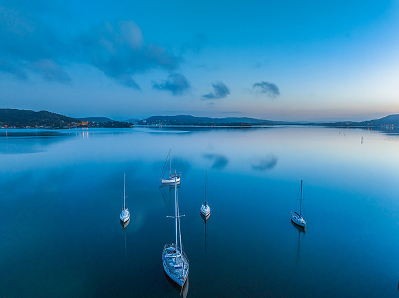 Aerial sunrise waterscape with boats, reflections and low cloud
