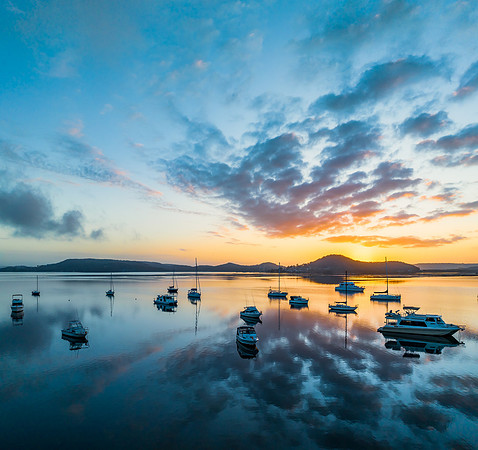 Aerial sunrise waterscape with boats, reflections and low cloud