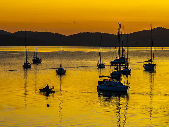 Aerial sunrise over the water with boats and clouds