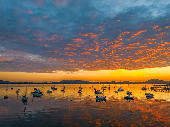 Aerial sunrise over the water with boats and clouds