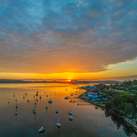 Aerial sunrise over the water with boats and clouds