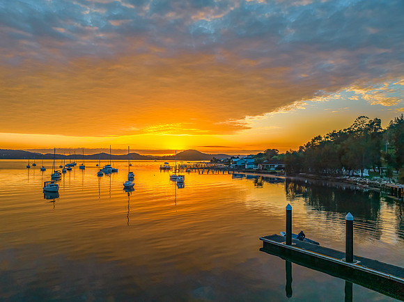 Aerial sunrise over the water with boats and clouds