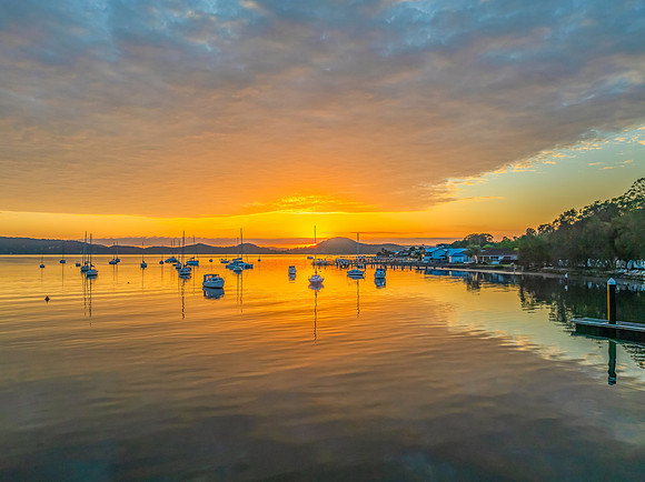 Aerial sunrise over the water with boats and clouds