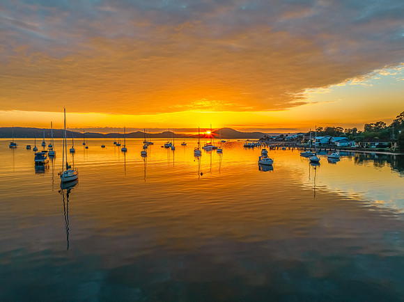 Aerial sunrise over the water with boats and clouds