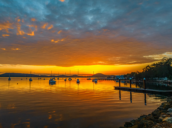 Aerial sunrise over the water with boats and clouds