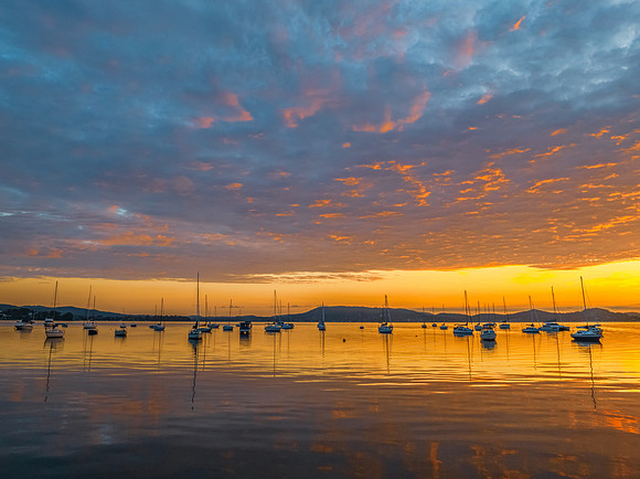 Aerial sunrise over the water with boats and clouds