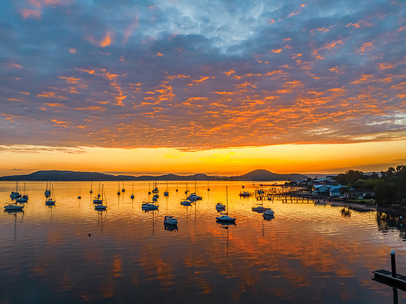 Aerial sunrise over the water with boats and clouds