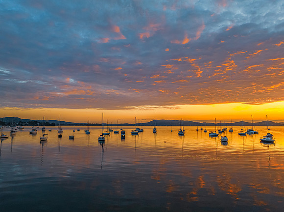 Aerial sunrise over the water with boats and clouds