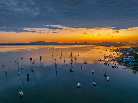 Aerial sunrise over the water with boats and clouds