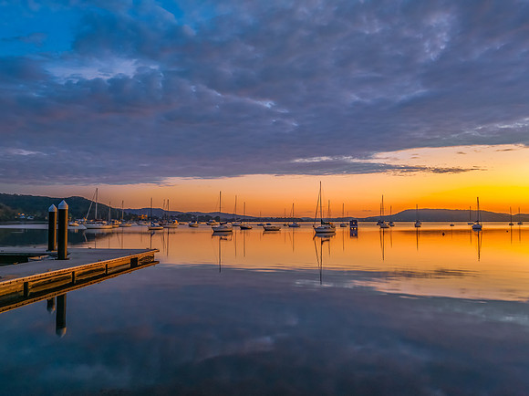 Aerial sunrise over the water with boats and clouds
