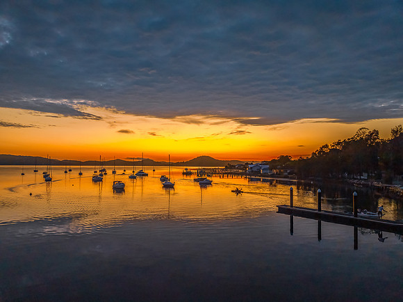 Aerial sunrise over the water with boats and clouds