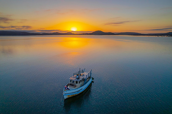 Sunrise waterscape with a boat, soft clouds and golden glow