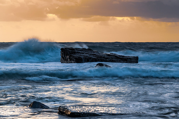 Moody sunrise seascape with clouds at the rocky inlet
