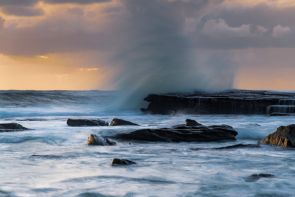 Moody sunrise seascape with clouds at the rocky inlet