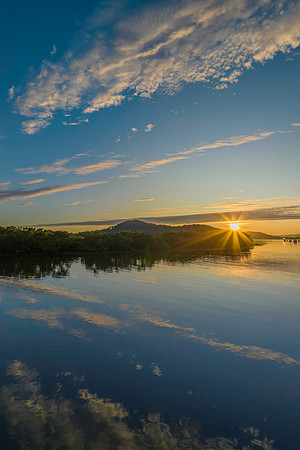 Sunburst and cloud reflections over the water