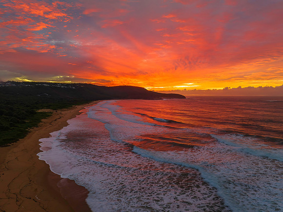 Cloud covered sunrise at the seaside in pink and blue