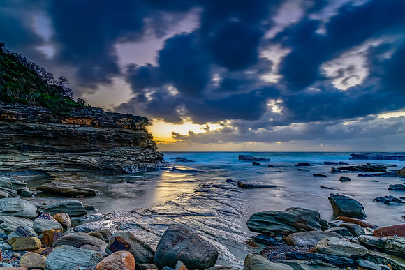 Moody sunrise seascape with clouds at the rocky inlet