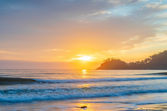 Sunrise at the seaside with cloud cover and seaweed