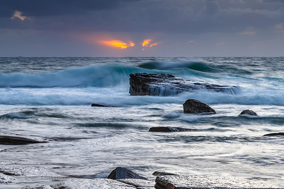 Moody sunrise seascape with clouds and casscades over the rock p
