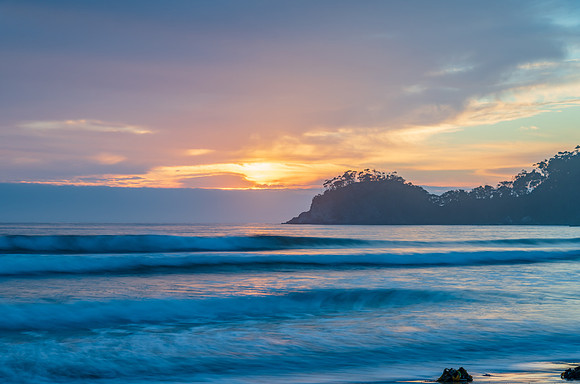 Sunrise at the seaside with cloud cover and seaweed