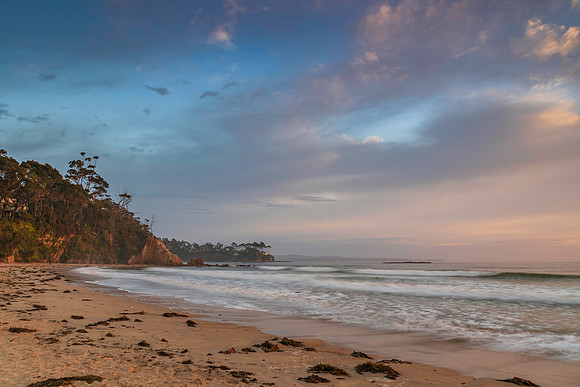 Sunrise at the seaside with cloud cover and seaweed