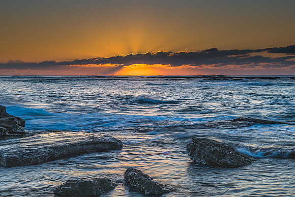 Sunrise Seascape with sunbeams through the low cloud bank