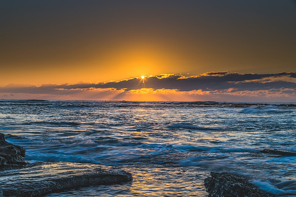 Sunrise Seascape with a sunburt through the low cloud bank
