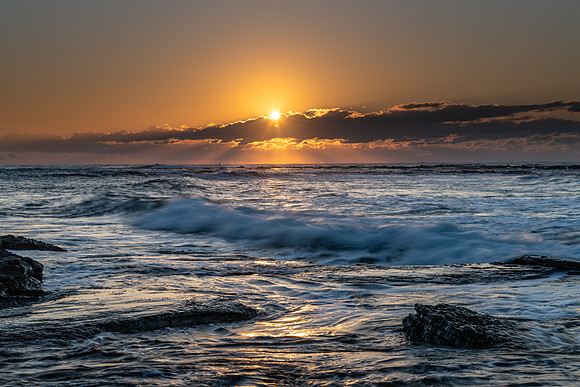 Sunrise Seascape with a sunburt through the low cloud bank