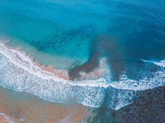 Top down at the seaside with waves, rocks and seaweed