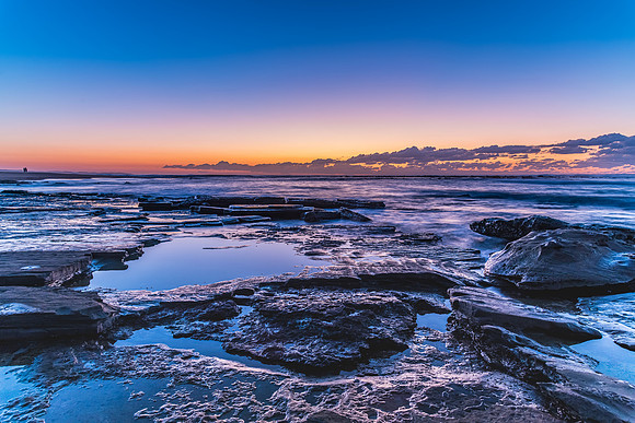 Dawn Seascape with a soft pink horizon and low cloud bank