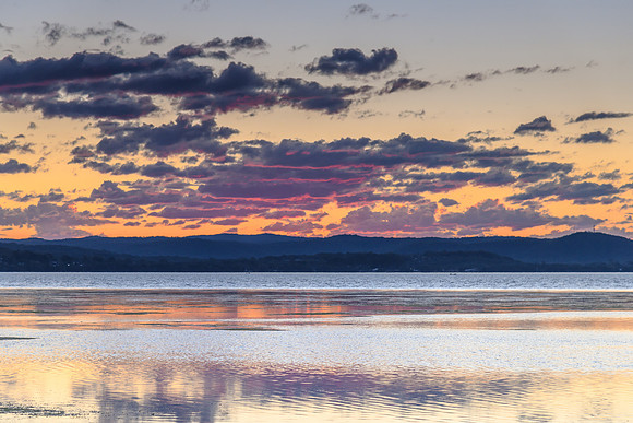 Sunset lights up the clouds in pink and purple over the Lake