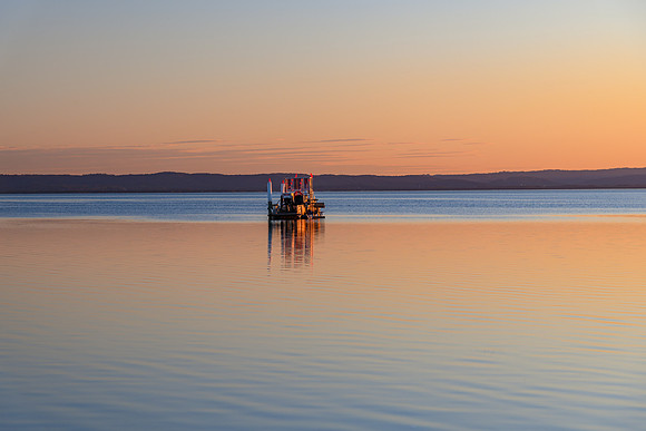 Soft Sunset over the Lake with Clear Skies and a Harvester