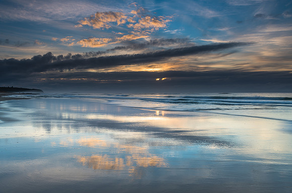 Sunrise Seascape with Clouds and Reflections on the Beach