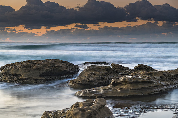 Sunrise seascape with rocks and a low cloud bank