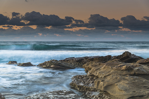 Sunrise seascape with rocks and a low cloud bank