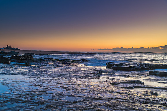 Sunrise seascape with a low cloud bank from rock platform